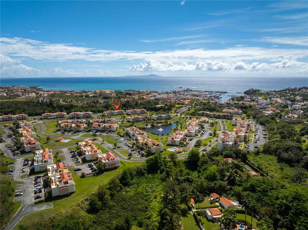 An aerial view shows a residential complex with multiple buildings, a pond, and ocean views — 180 PALMAS DRIVE UNIT 60-D, HUMACAO, PR