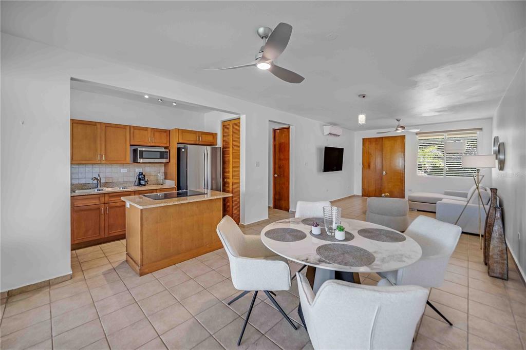 An open-concept kitchen and dining area featuring wooden cabinets, a central island, and tile flooring — 180 PALMAS DRIVE UNIT 60-D, HUMACAO, PR