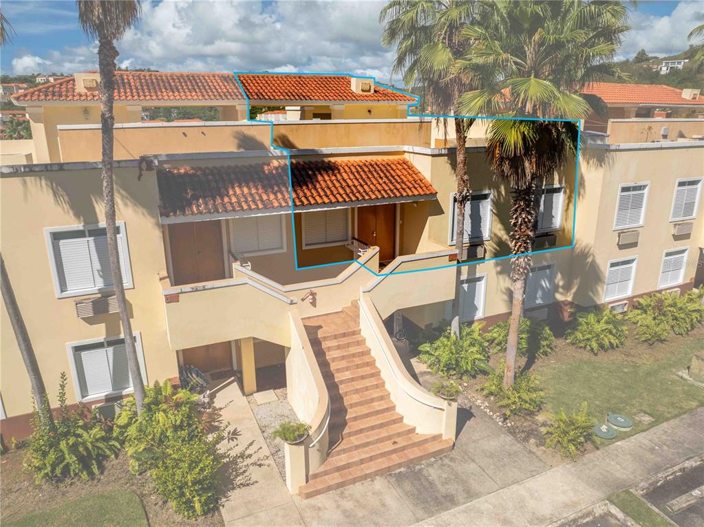 An exterior view of a two-story stucco apartment building with a tiled roof and stairs — 180 PALMAS DRIVE UNIT 60-D, HUMACAO, PR