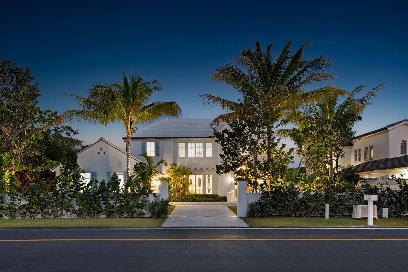 A two-story white house with palm trees and a paved driveway at twilight — 2219 Ibis Isle Road E, Palm Beach FL 33480, PALM BEACH, FL