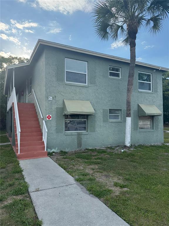 A two-story green stucco apartment building features an exterior staircase and a palm tree — 712 MICHIGAN CT UNIT 3, ST CLOUD, FL