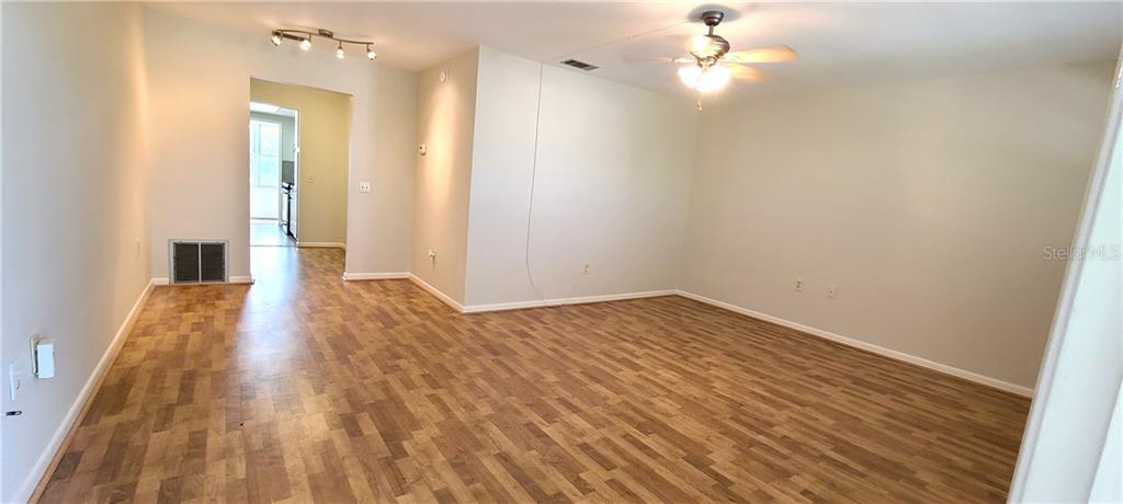 An empty room with wood-look flooring, a ceiling fan, and a doorway leading to another area — 911 WASHINGTON AVENUE UNIT 305, LARGO, FL