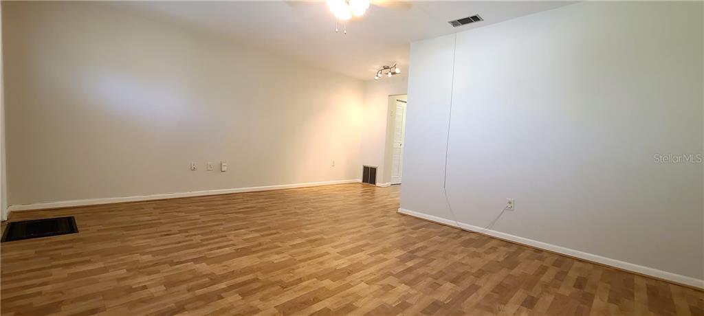 An empty room features light gray walls, wood-look flooring, and a ceiling fan — 911 WASHINGTON AVENUE UNIT 305, LARGO, FL