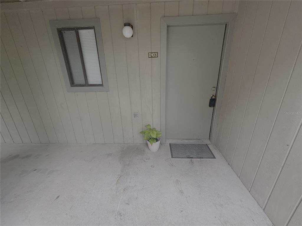 An exterior view of a residential unit entrance with a gray door labeled D103 — 81 SE 16TH AVENUE UNIT D-103, GAINESVILLE, FL