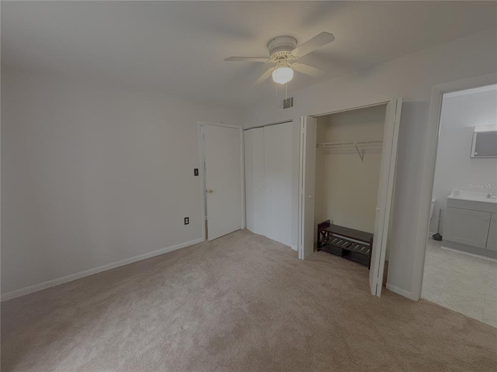 A bedroom features beige carpeting, a ceiling fan, a closet, and an attached bathroom — 81 SE 16TH AVENUE UNIT D-103, GAINESVILLE, FL