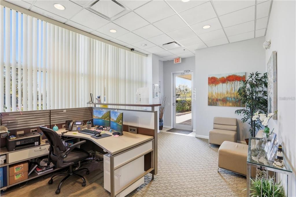 An office space features a desk with dual monitors, a seating area, and a glass door — 10967 LAKE UNDERHILL ROAD UNIT 112, ORLANDO, FL