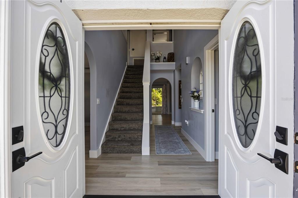 An entryway with double doors, light wood flooring, a carpeted staircase, and arched wall openings — 1681 DAWNVIEW STREET, NORTH PORT, FL