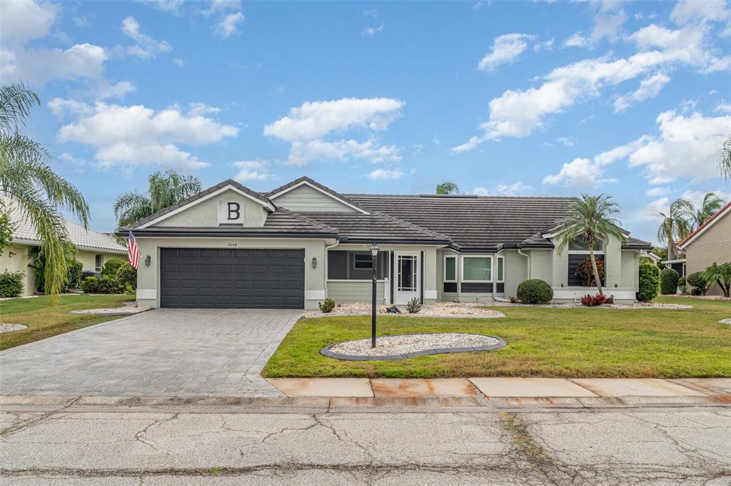 A single-story house with a dark garage door, light siding, and a paved driveway — 2048 BERRY ROBERTS DRIVE, SUN CITY CENTER, FL