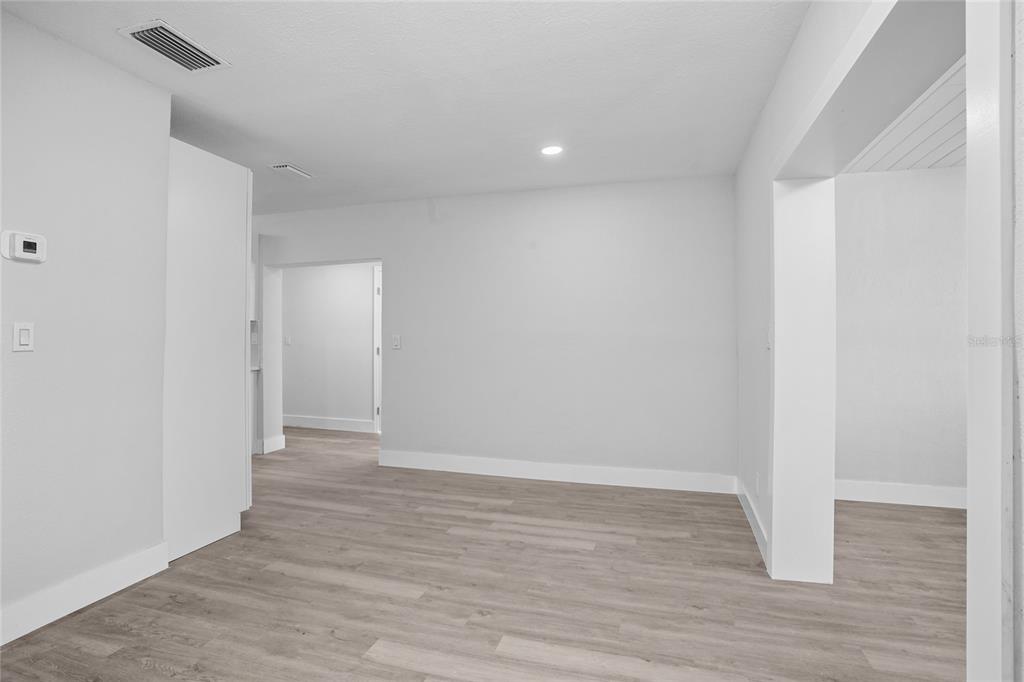 An interior view showing a room with light gray walls, white trim, and wood-look flooring — 630 180TH AVENUE E, REDINGTON SHORES, FL
