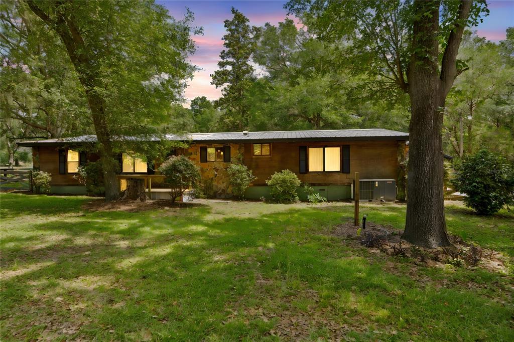 A single-story house with wood siding and a metal roof sits in a grassy yard — 27137 LAMBETH ROAD, BROOKSVILLE, FL