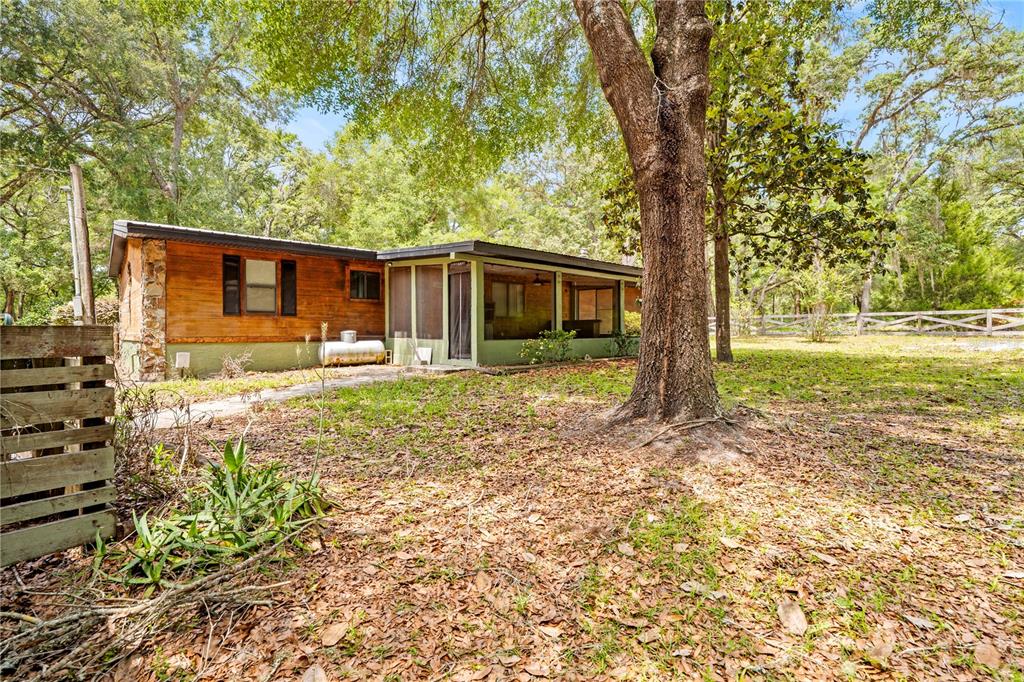 A single-story house with wood siding, a stone corner, and a screened-in porch — 27137 LAMBETH ROAD, BROOKSVILLE, FL