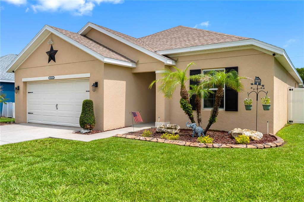 The exterior of a tan house features a garage, a front entrance, and landscaping — 3518 SAN MOISE PLACE, PLANT CITY, FL