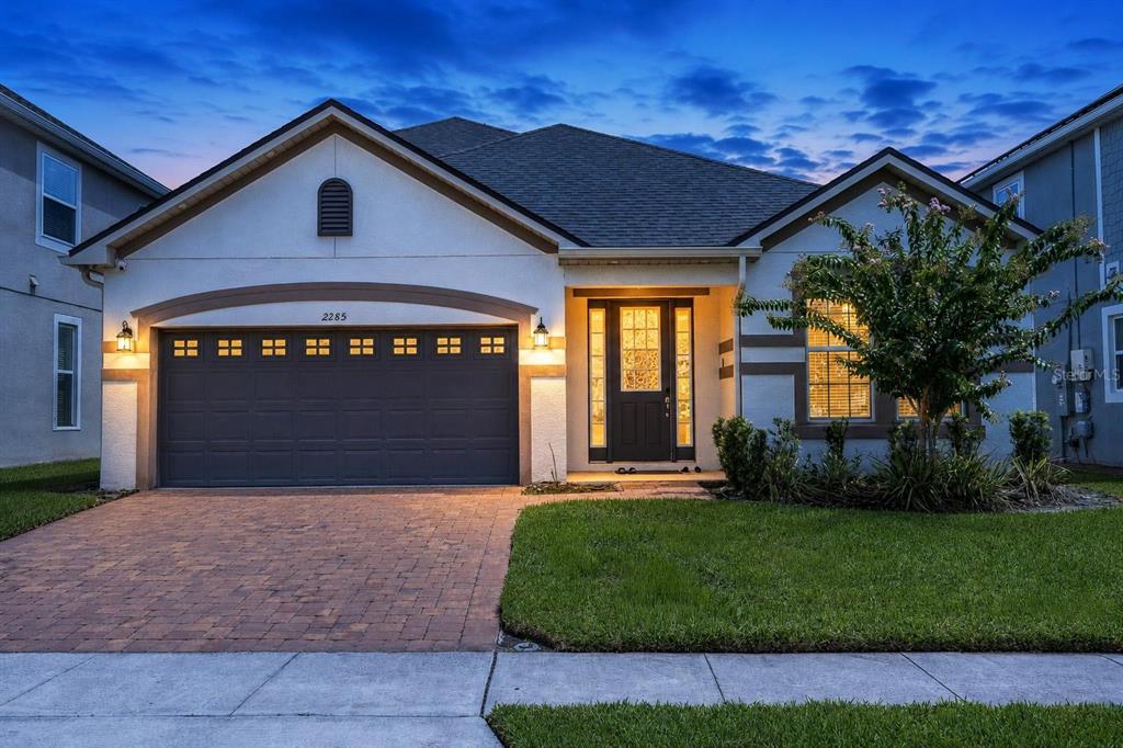 A single-story house with a two-car garage, a paved driveway, and a front entryway — 2285 CENTERRA LOOP, KISSIMMEE, FL