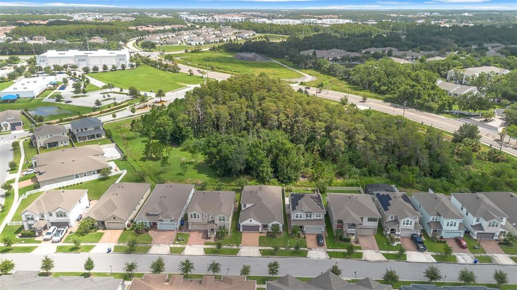 An aerial view shows a row of suburban houses bordering a large wooded area — 2285 CENTERRA LOOP, KISSIMMEE, FL