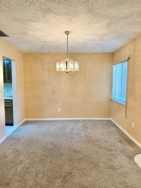 A dining room with beige walls, gray carpeting, and a decorative hanging light fixture — 101 GRAND PLAZA DRIVE UNIT F4, ORANGE CITY, FL