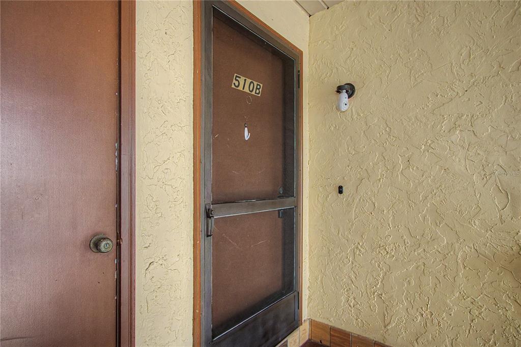 A brown door and a screen door labeled 510B sit against a textured yellow wall — 510 SILVER COURSE UNIT B, OCALA, FL