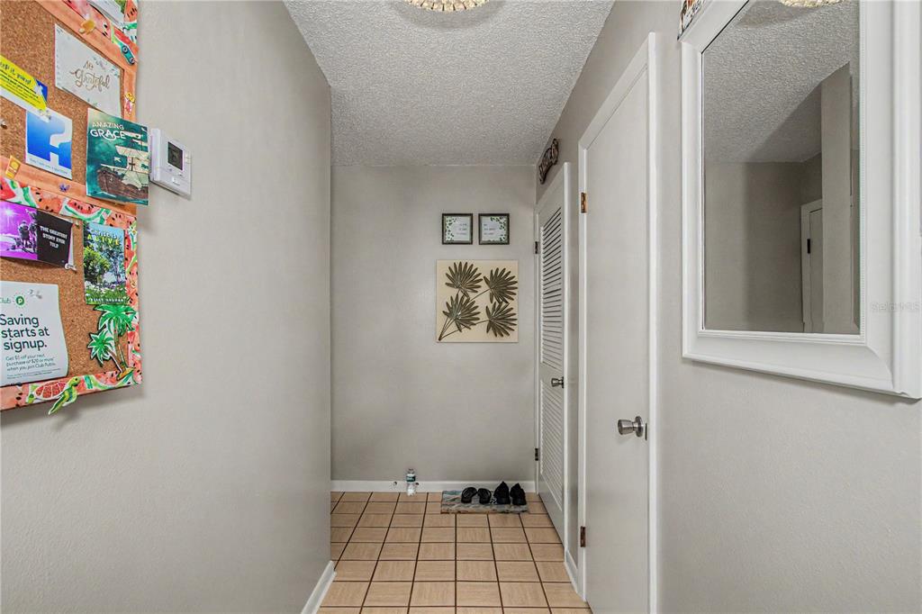 A tiled entryway features a cork bulletin board, a wall mirror, and a louvered door — 510 SILVER COURSE UNIT B, OCALA, FL