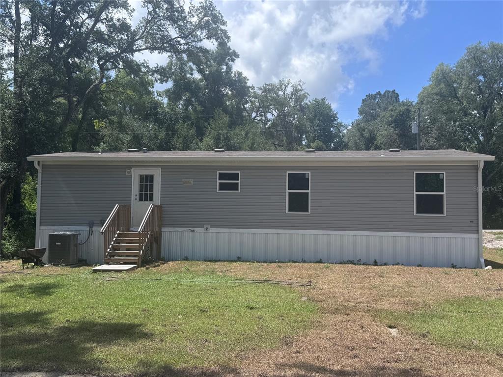 A gray manufactured home with a wooden staircase and an air conditioning unit outside — 11801 NW 20TH STREET, OCALA, FL