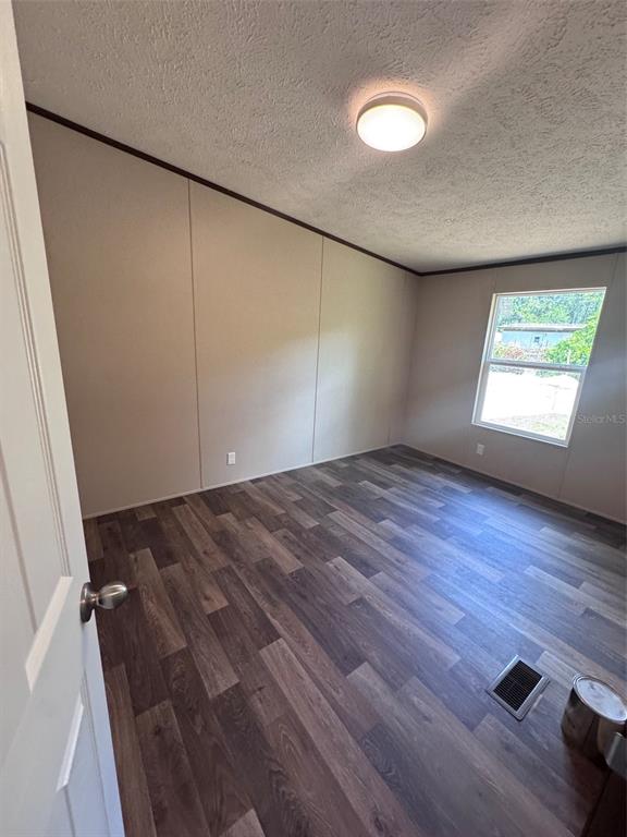 An empty bedroom features wood-look flooring, beige walls, a ceiling light, and a single window — 11801 NW 20TH STREET, OCALA, FL