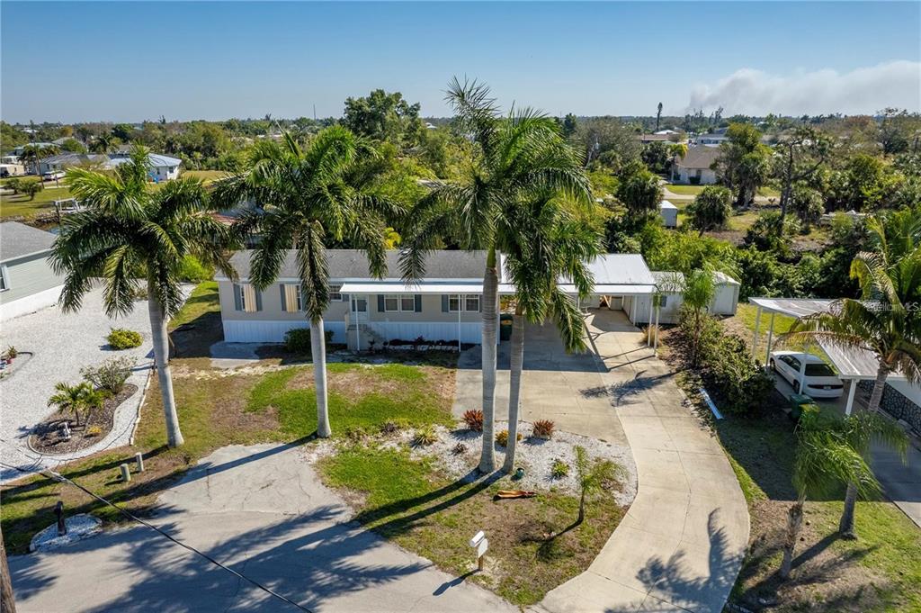 An aerial view of a single-story mobile home with palm trees and a concrete driveway — 3004 BAMBOO COURT, PUNTA GORDA, FL