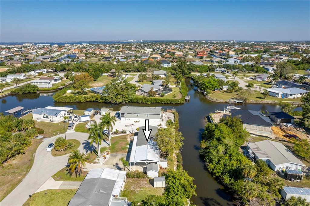 An aerial view shows a waterfront house with a screened patio along a canal — 3004 BAMBOO COURT, PUNTA GORDA, FL