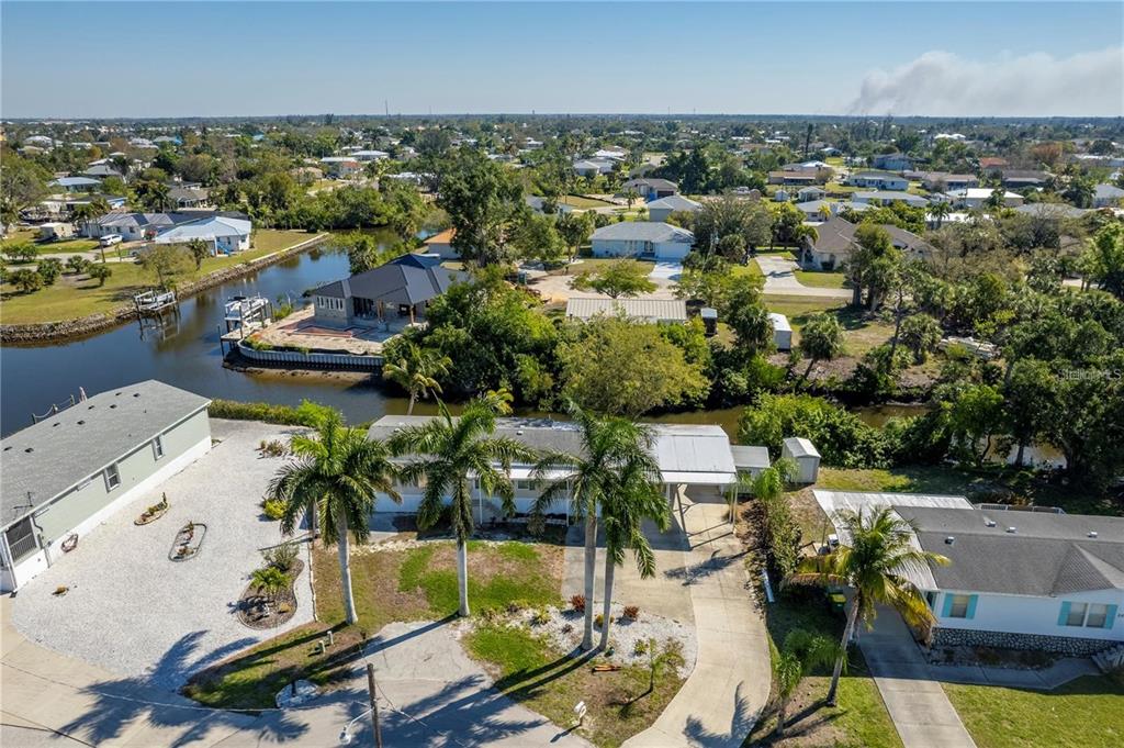 An aerial view shows a residential neighborhood with houses, palm trees, and a canal — 3004 BAMBOO COURT, PUNTA GORDA, FL