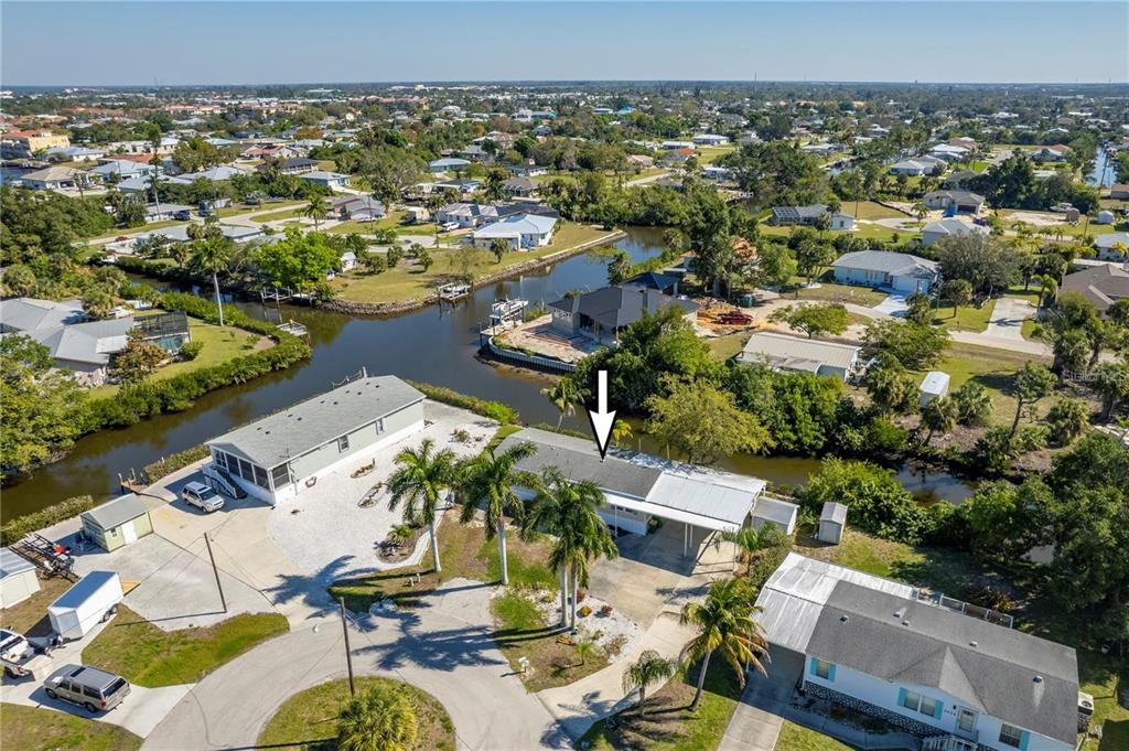 An aerial view shows a single-story house with a carport situated along a canal — 3004 BAMBOO COURT, PUNTA GORDA, FL