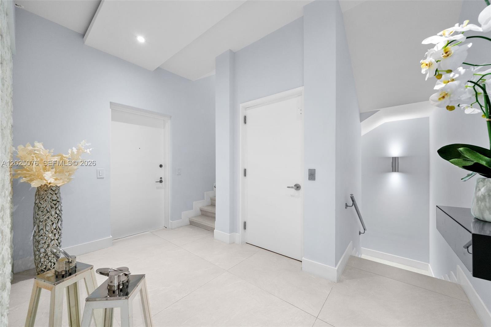 A modern entryway features light-colored tile floors, white walls, two doors, and a staircase — 650 NE 32nd St, Miami FL 33137, MIAMI, FL