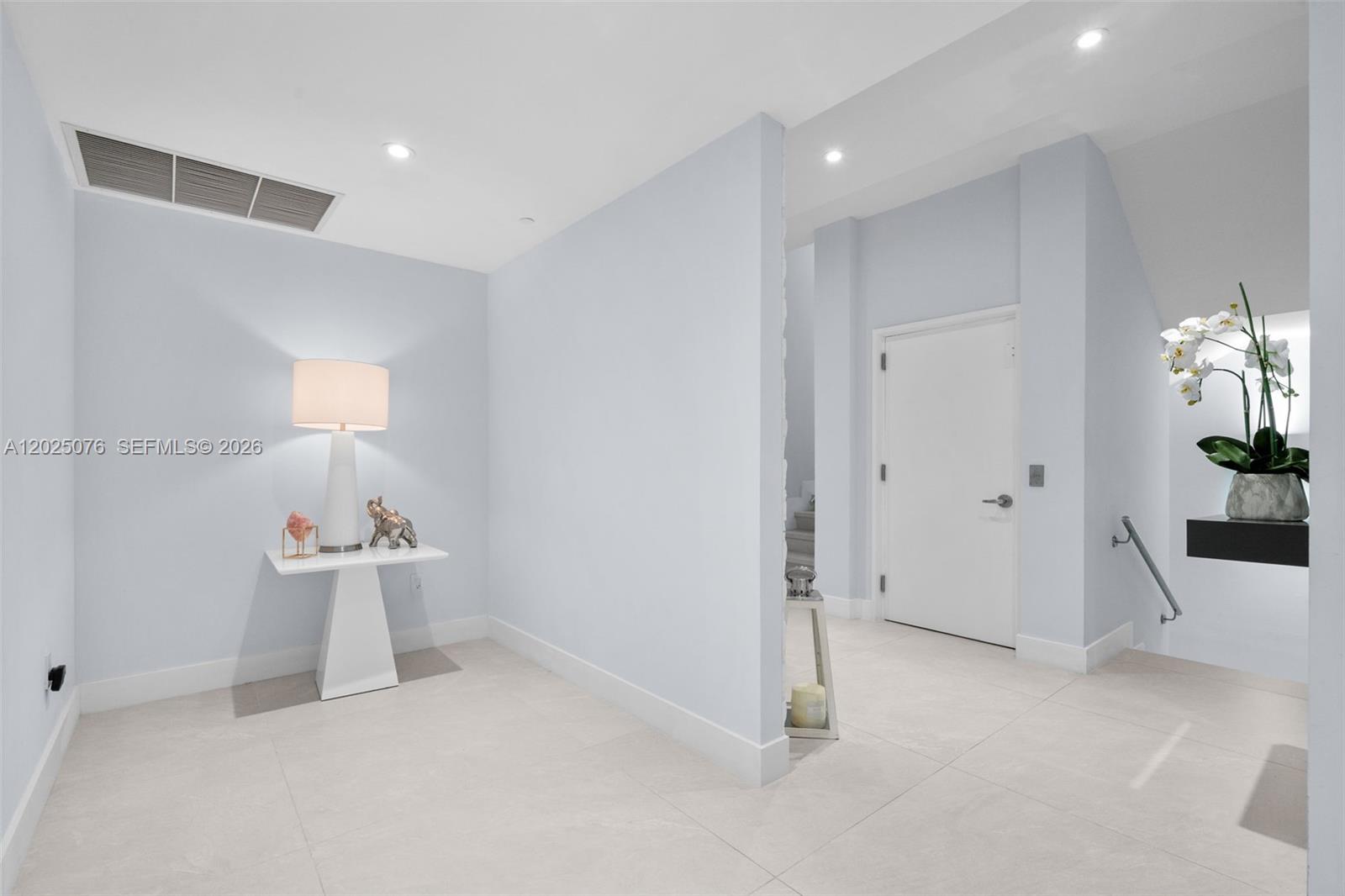 A minimalist entryway features light blue walls, white tile flooring, and a small console table — 650 NE 32nd St, Miami FL 33137, MIAMI, FL