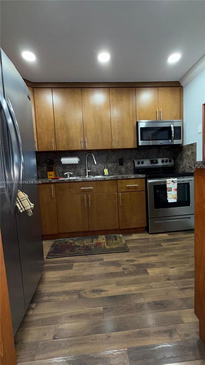 A kitchen features wood cabinets, stainless steel appliances, and wood-look flooring — 1075 W 68th St # 403, Hialeah FL 33014, HIALEAH, FL
