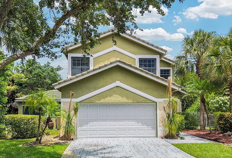A two-story house with green stucco siding, a white garage door, and a paved driveway — 8020 NW 70th Avenue, Parkland FL 33067, PARKLAND, FL