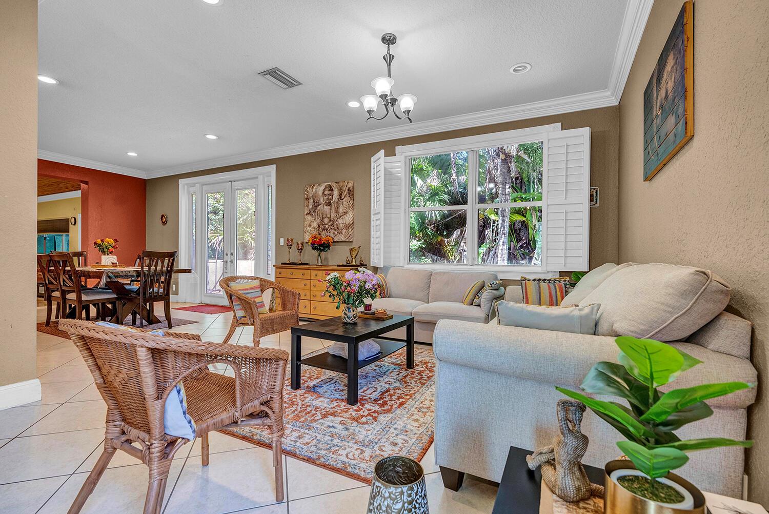 A living room with a beige sofa, wicker chairs, and a dining area in the background — 8020 NW 70th Avenue, Parkland FL 33067, PARKLAND, FL