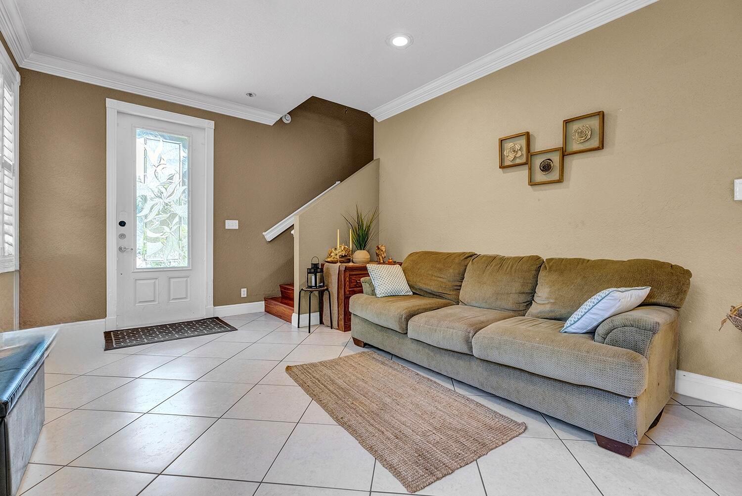 A living room features a tan sofa, tiled floors, and a front door with glass — 8020 NW 70th Avenue, Parkland FL 33067, PARKLAND, FL