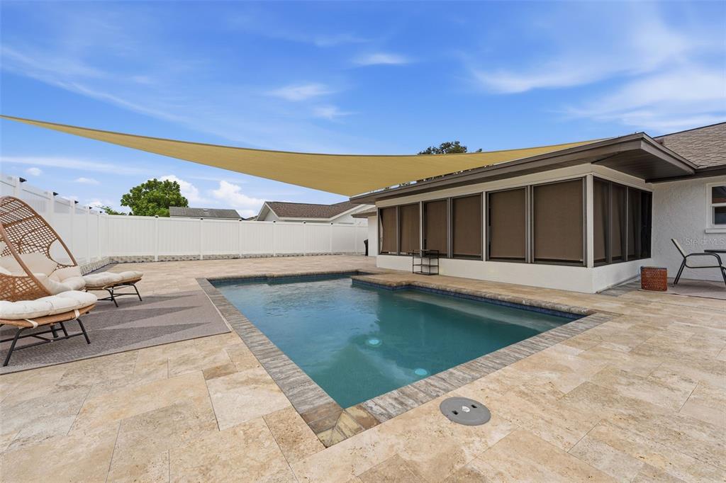 A backyard features a rectangular swimming pool, stone patio, and a large tan shade sail — 6020 10TH AVENUE W, BRADENTON, FL