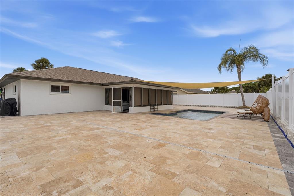 A backyard features a stone patio, a swimming pool, a screened lanai, and a shade sail — 6020 10TH AVENUE W, BRADENTON, FL