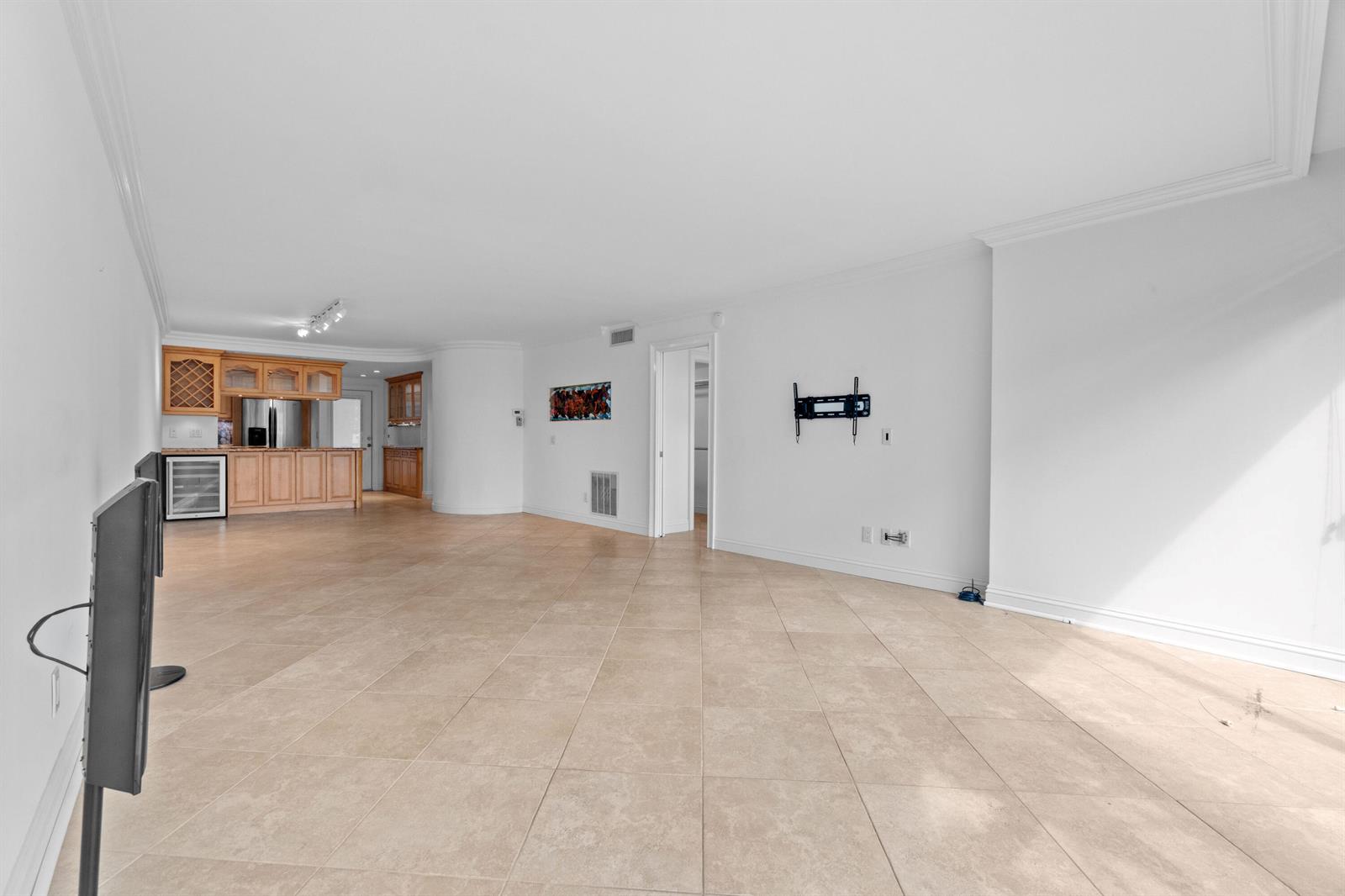 An open-concept living area features light-colored tile flooring, white walls, and a wooden kitchen bar — 2731 NE 14th St Causeway # 115, Pompano Beach FL 33062, POMPANO BEACH, FL
