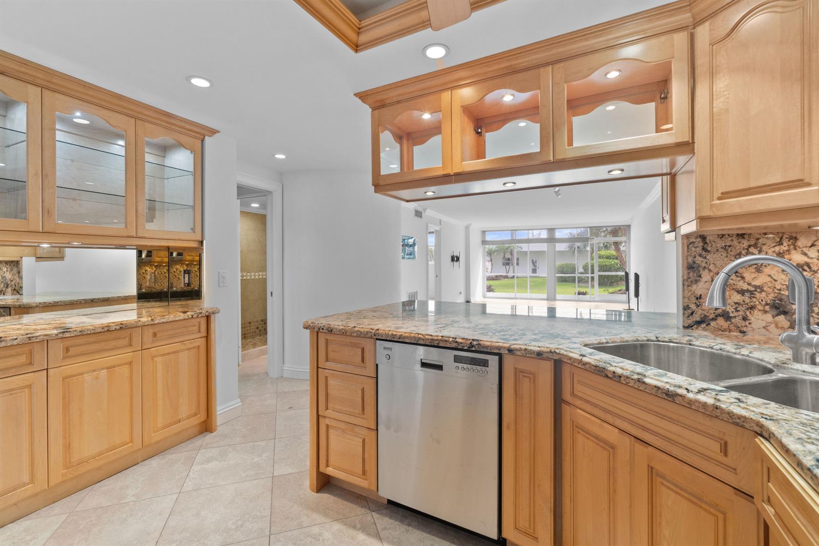 A kitchen features light wood cabinets, granite countertops, a stainless steel dishwasher, and tile flooring — 2731 NE 14th St Causeway # 115, Pompano Beach FL 33062, POMPANO BEACH, FL