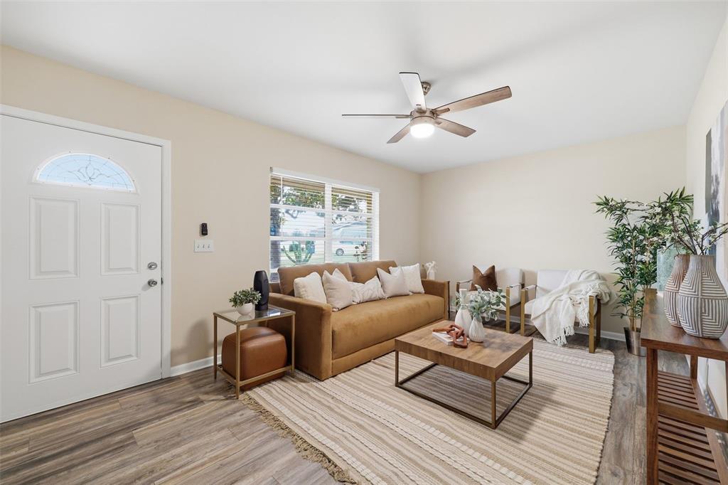 A living room features a brown sofa, a coffee table, and wood-look flooring — 2327 W KNOLLWOOD PLACE, TAMPA, FL