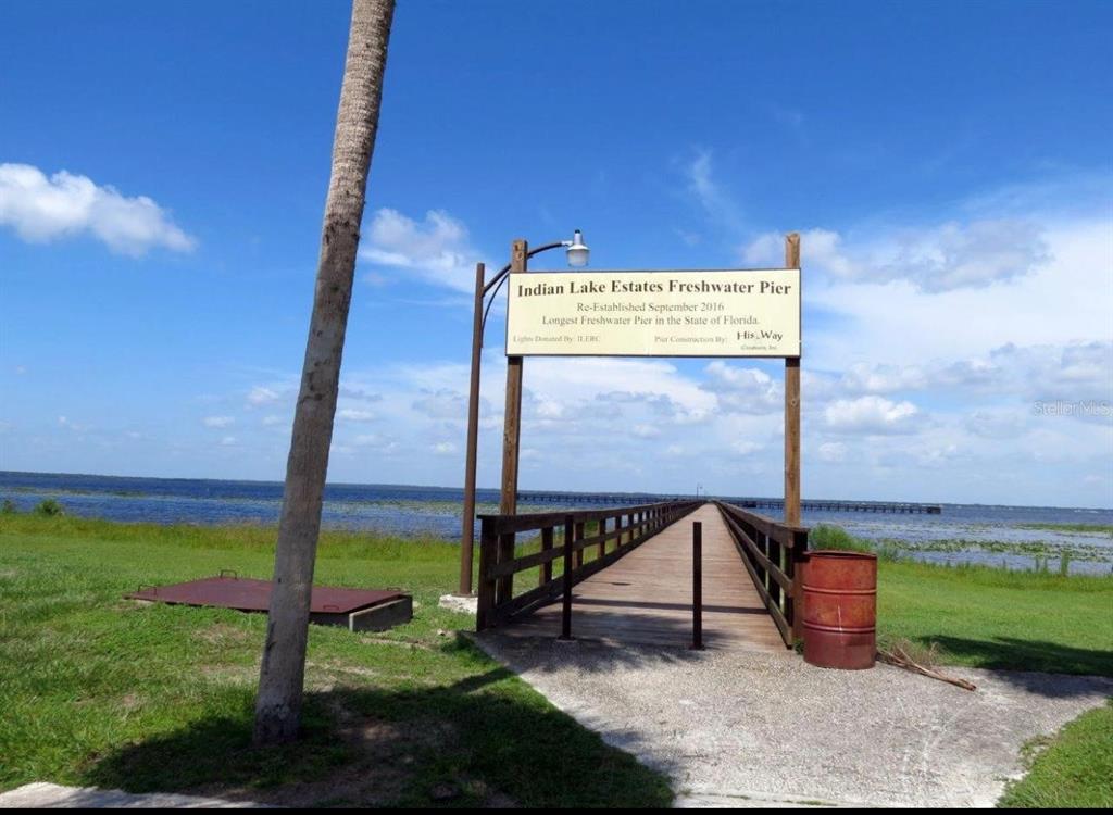 A wooden pier extends into a large lake under a blue sky with scattered clouds — 0 PLUMOSA DRIVE, INDIAN LAKE ESTATES, FL