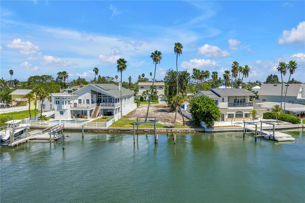 An aerial view shows waterfront houses and a vacant lot along a canal with docks — 315 10TH AVENUE, INDIAN ROCKS BEACH, FL