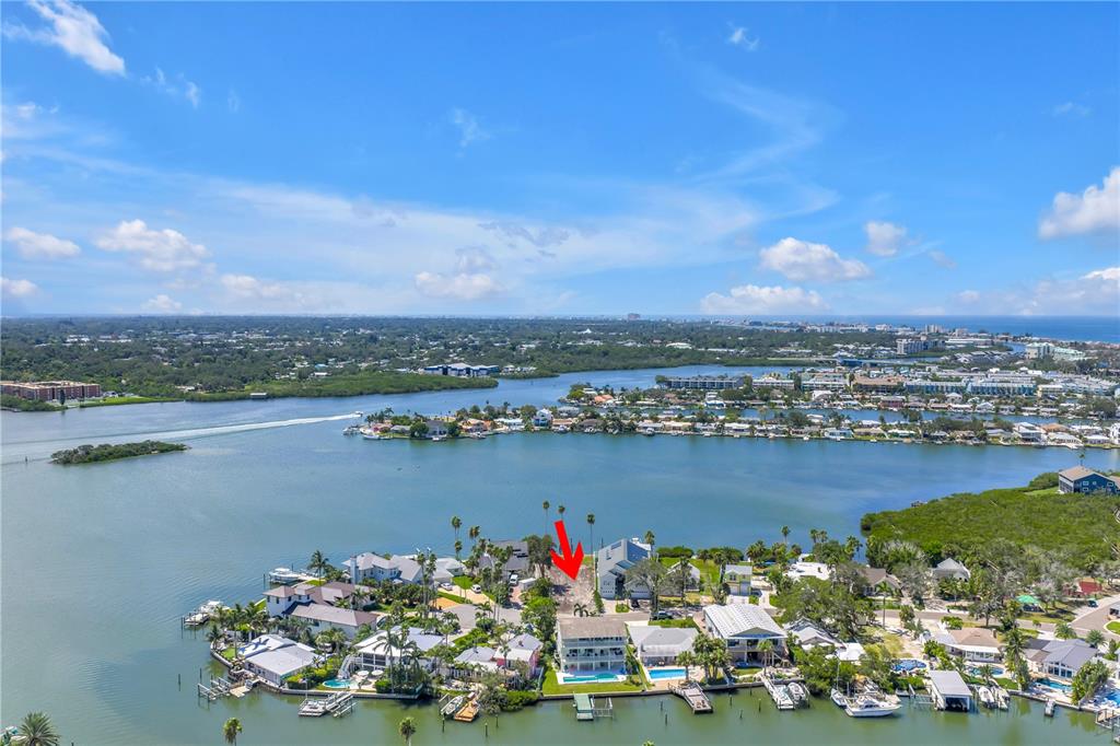 An aerial view shows a waterfront residential neighborhood with a red arrow pointing toward a house — 315 10TH AVENUE, INDIAN ROCKS BEACH, FL