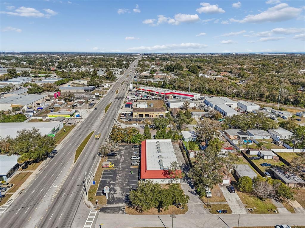An aerial view shows a commercial building with a red roof along a busy road — 8625 66TH STREET N, PINELLAS PARK, FL