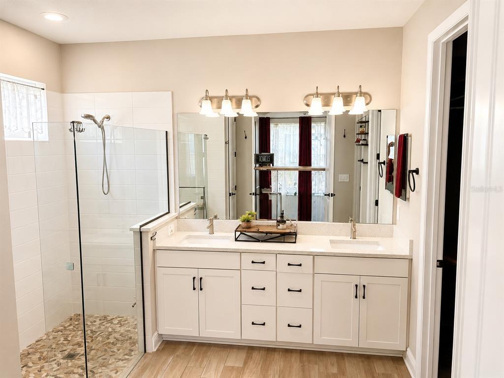 A bathroom features a double vanity with white cabinets, quartz countertops, and a glass shower — 12571 NIGHT VIEW DRIVE, SARASOTA, FL