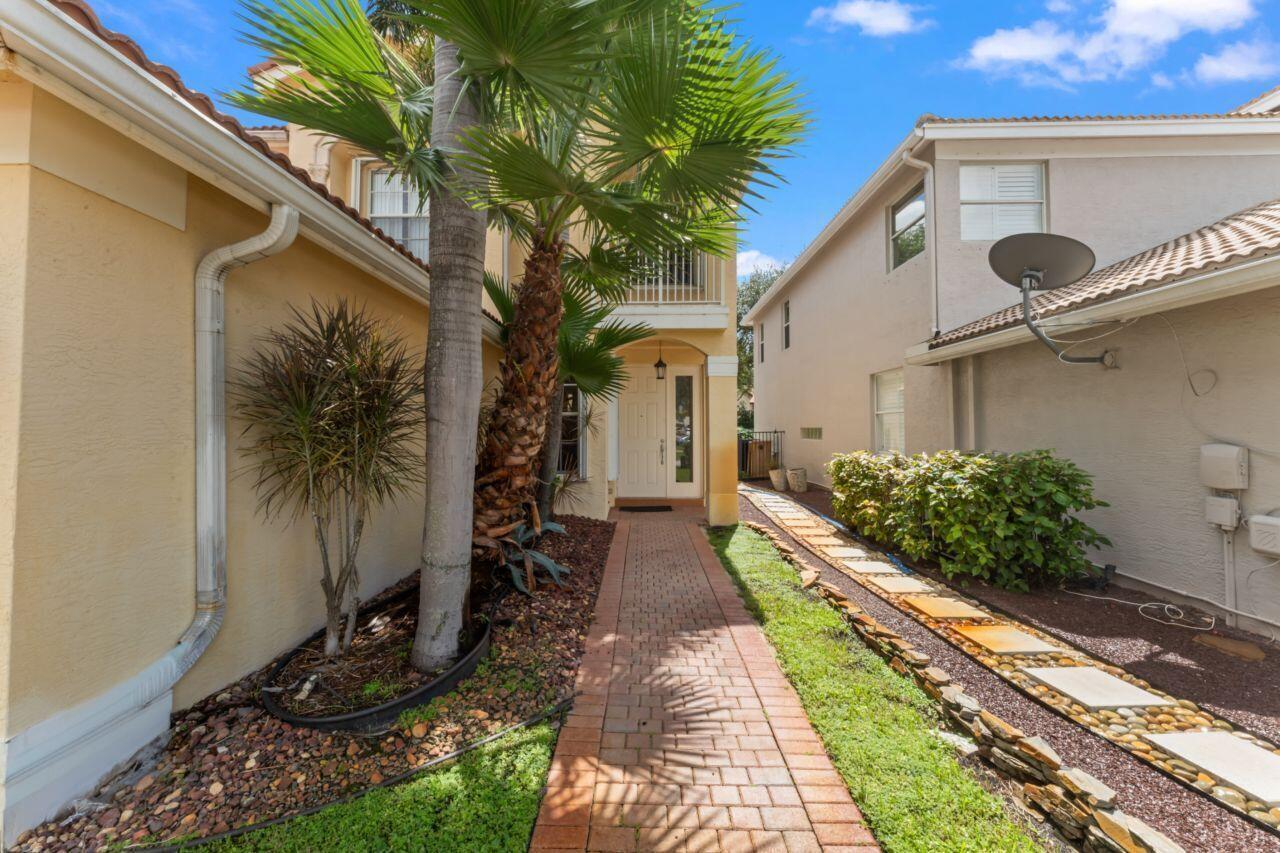 A brick walkway leads to the front entrance of a two-story home with palm trees — 8492 Breezy Oak Way, Boynton Beach FL 33473, BOYNTON BEACH, FL