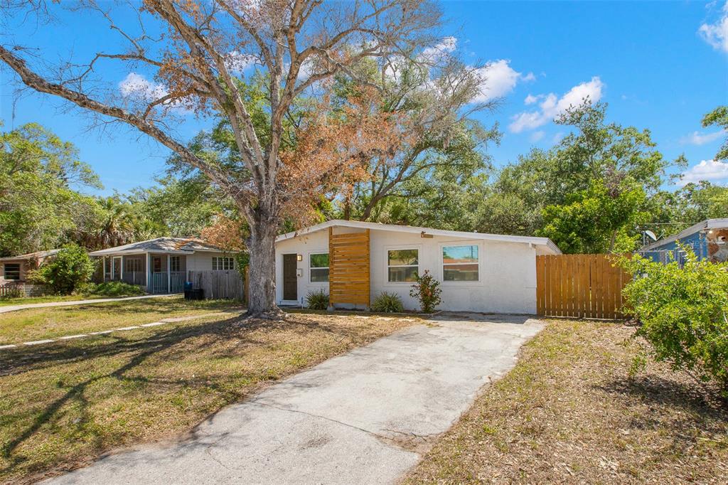 A single-story white house with a concrete driveway and a wooden privacy fence — 2356 KINGSTON STREET S, ST PETERSBURG, FL