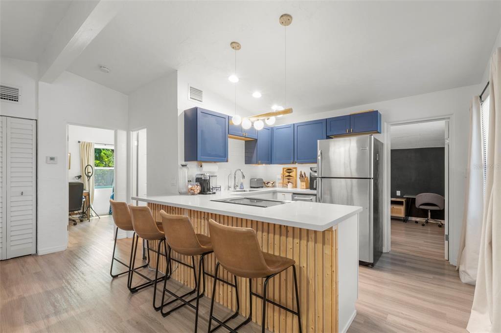 A kitchen features blue cabinets, a white countertop, and a wood-slatted breakfast bar with stools — 2356 KINGSTON STREET S, ST PETERSBURG, FL