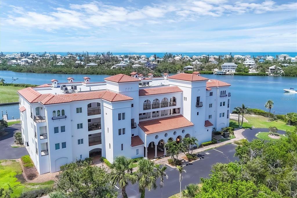 An aerial view of a multi-story white building with a red tile roof near water — 11100 HACIENDA DEL MAR BOULEVARD UNIT G-304, PLACIDA, FL