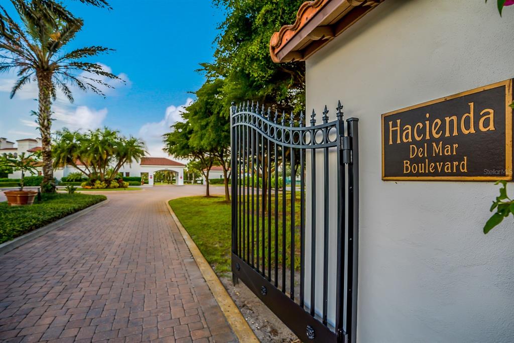 A black metal gate stands at the entrance of a paved driveway with palm trees — 11100 HACIENDA DEL MAR BOULEVARD UNIT G-304, PLACIDA, FL