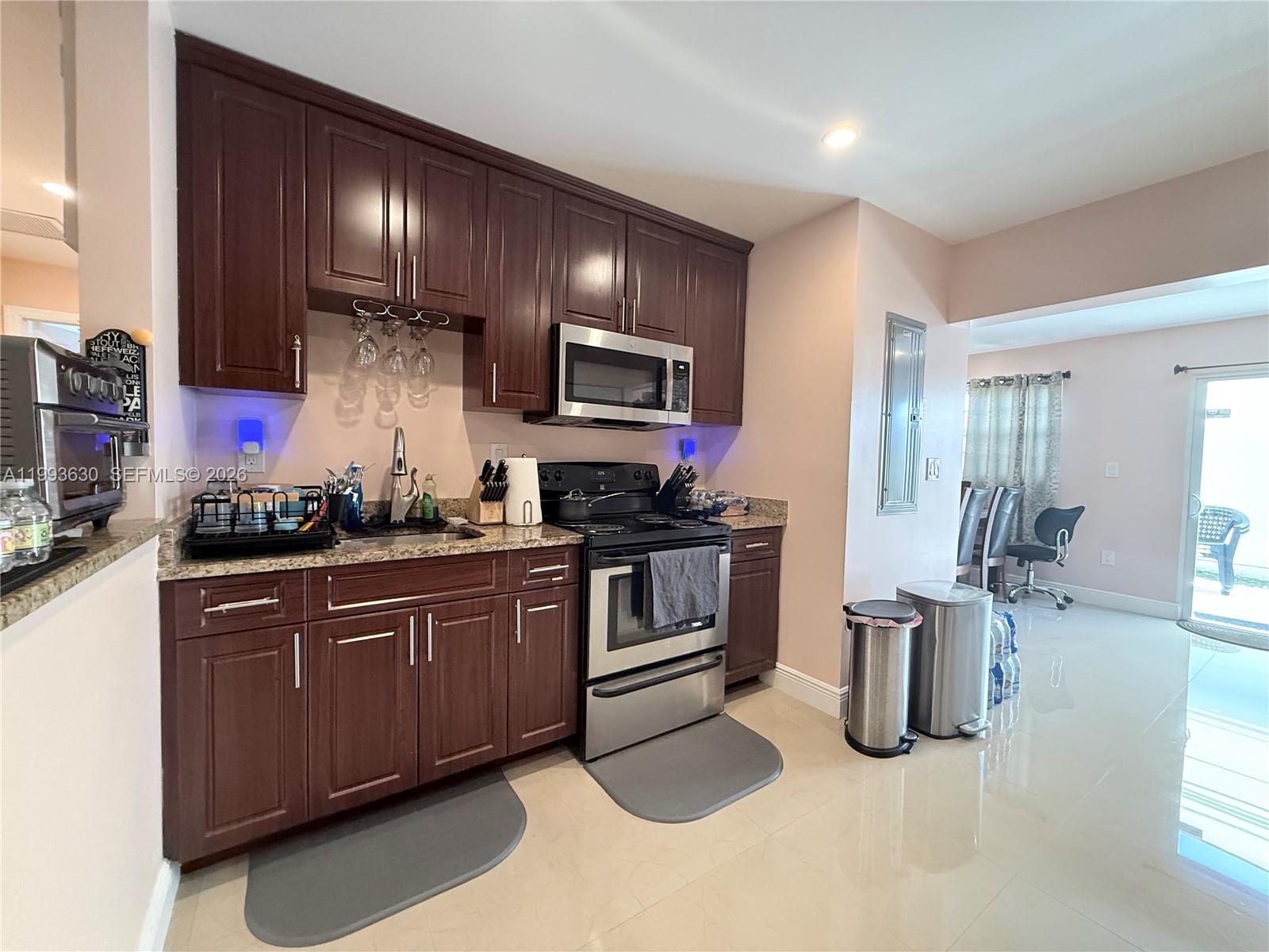 A kitchen features dark wood cabinets, stainless steel appliances, and light-colored tile flooring — 1878 NW 45th Ct, Tamarac FL 33309, TAMARAC, FL
