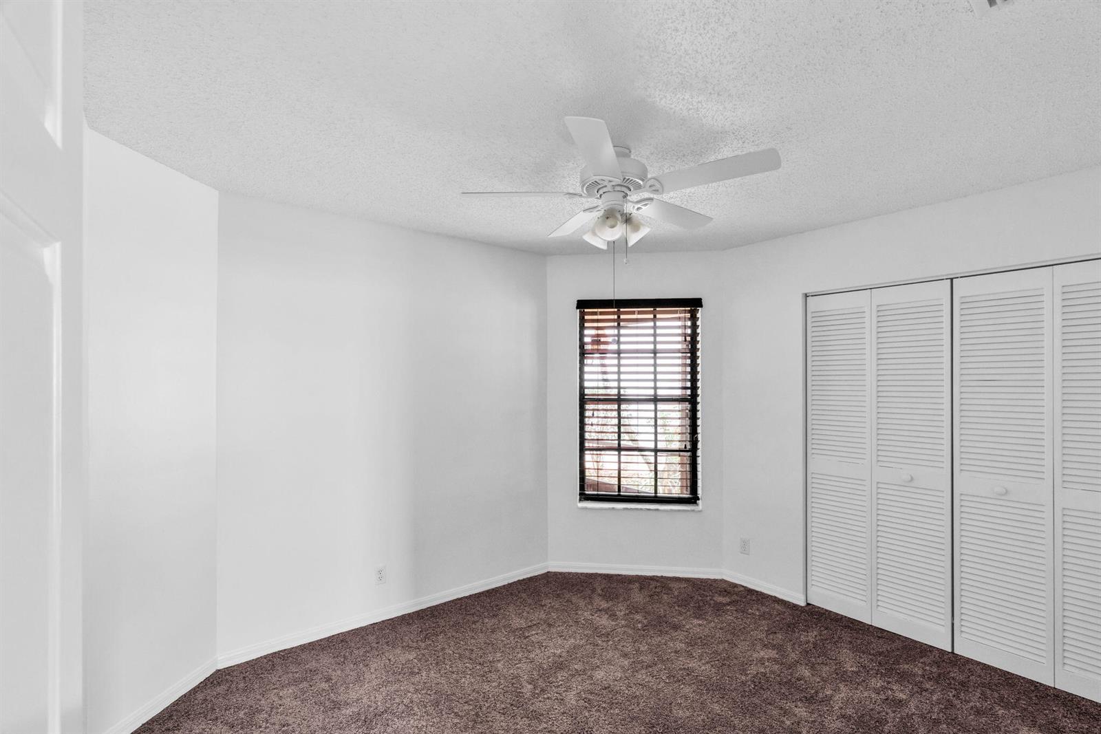 A bedroom with white walls, brown carpet, a ceiling fan, and white louvered closet doors — 12382 Pleasant Green Way, Boynton Beach FL 33437, BOYNTON BEACH, FL
